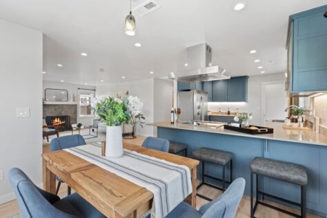 Interior 24th Ave Dining Room with wooden table, livingroom with fireplace and blue-grey kitchen 0020 211kb