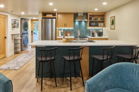 Basement kitchen with bar stools at counter.