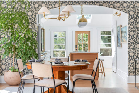 Round wooden dining room table with kitchen in background
