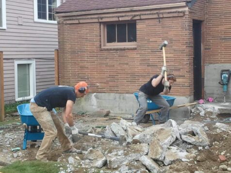 Crew using jack hammers to break up old house foundation