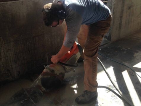 Man sawing newly poured foundation