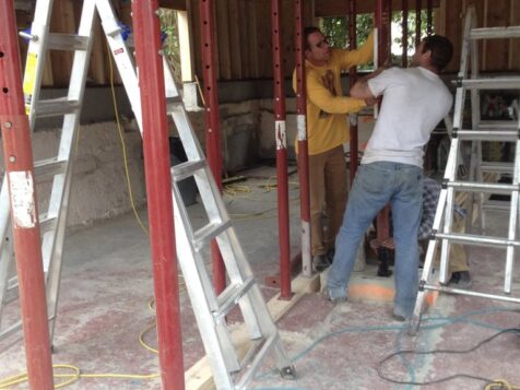 Man framing basement walls in recently lifted house