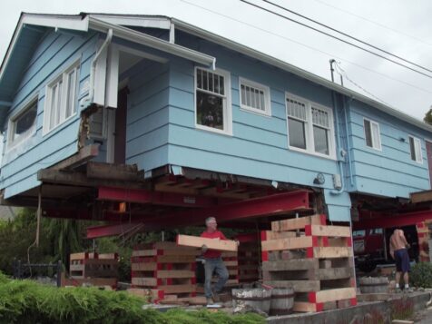 Blue house up on piers with man underneath