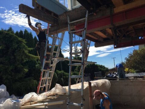 Man working on the underside of a lifted house