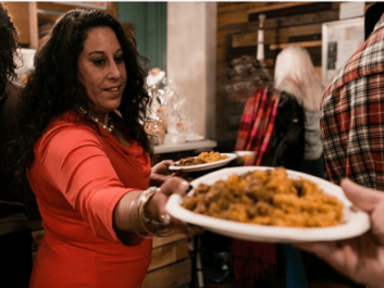 Aurora Commons Community A woman serves food to a hungry human